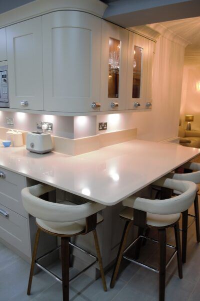 Worktop acts as an inviting breakfast bar with stools, under-cabinet lighting in the modern classic kitchen
