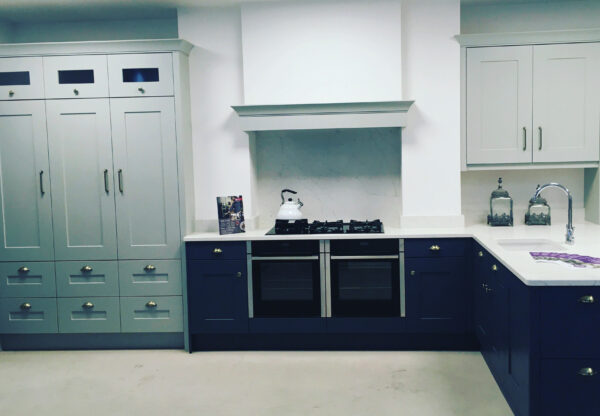 Shaker style kitchen that features cabinets in white and navy with white worktops, intergrated induction hob, and Silestone Integrity sink