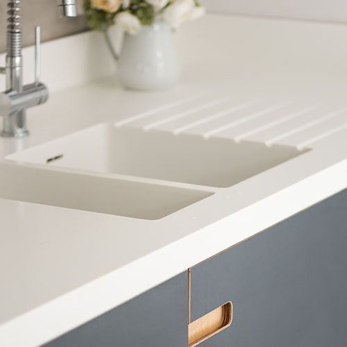 Close-Up of Moulded Sink that Seamlessly Integrates into Worktop, Dark Grey Cabinets with Brass Handles Peek Below