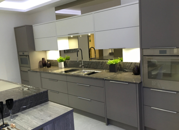 Double-Layered Sage Green Pull-Out Cabinet Drawers Overhead, Mirrored Splashback Next to Silver Kitchen Sink, Dark Avocado Green Lower Cabinets and Drawers, Integrated Double Oven, Under Cabinet Lighting