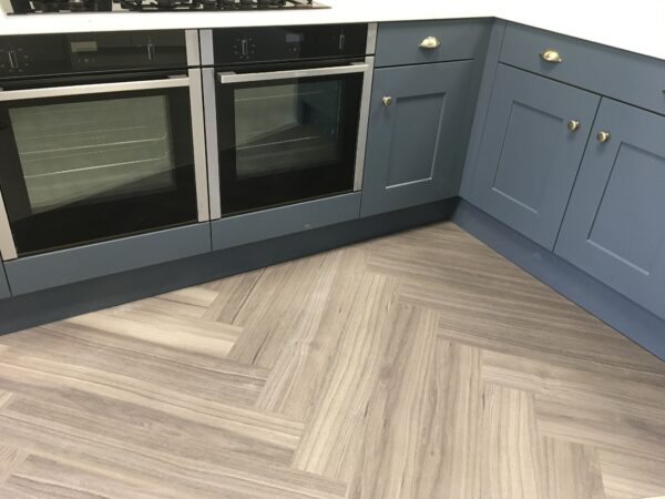 Karndean flooring in slatted warm wood colour. Matched with olive toned grey cabinets with gold fixtures, and integrated double ovens.
