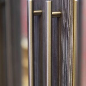 Close-up shot of a shiny silver handle and a dark wood-style bedroom furniture