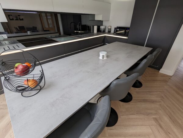 a Cavendish-designed kitchen featuring cabinet doors in Veneto Graphite Matt & Veneto White Matt with a handleless rail system. The worktops are Chromix Silver Laminate, complemented by warm wood-effect Karndean flooring.