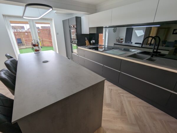Cavendish-designed kitchen featuring Veneto Graphite Matt and Veneto White Matt cabinet doors with a handleless rail system. The worktops are Chromix Silver Laminate, complemented by warm wood-effect Karndean flooring